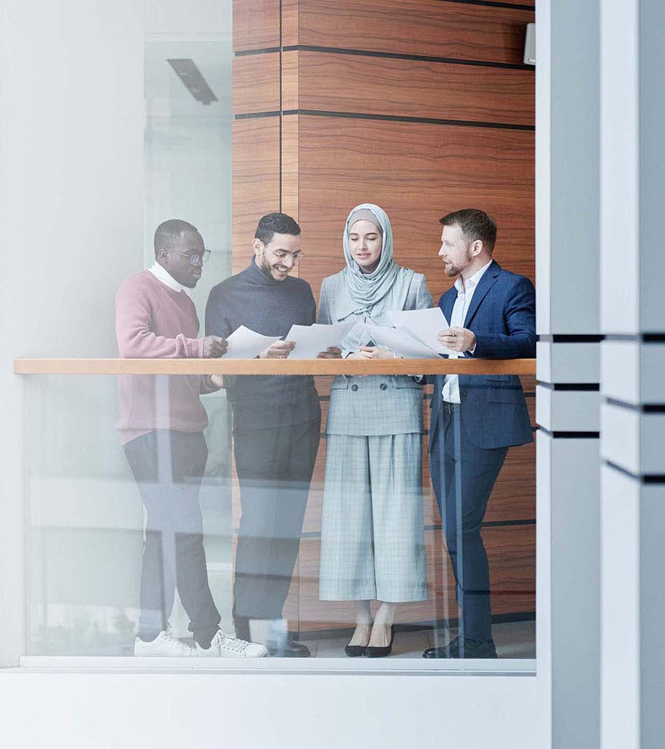 Four collaborators looking at reports all together standing up